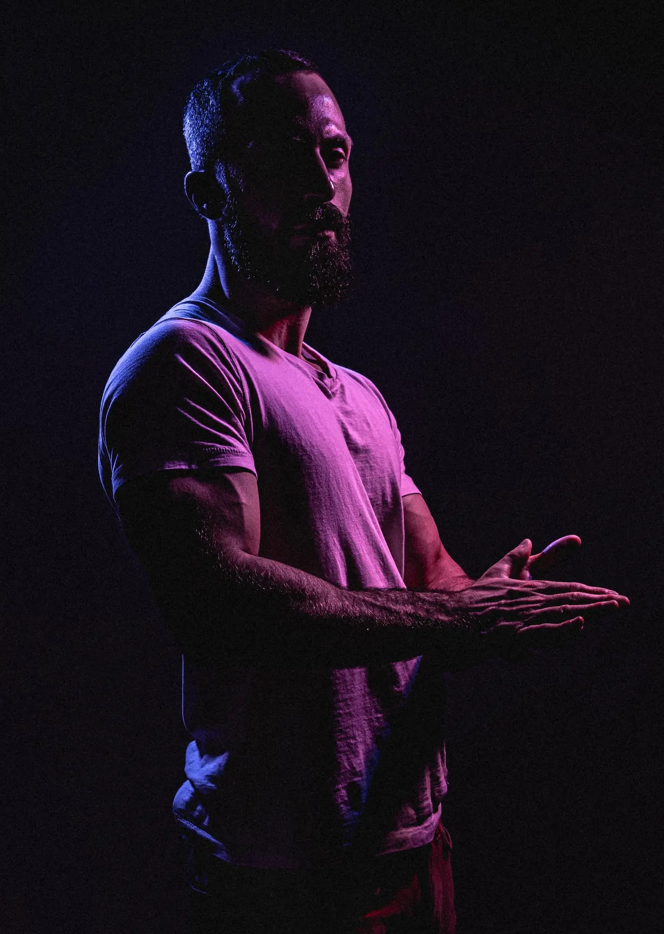 un hombre con las manos abiertas de pie en la oscuridad 