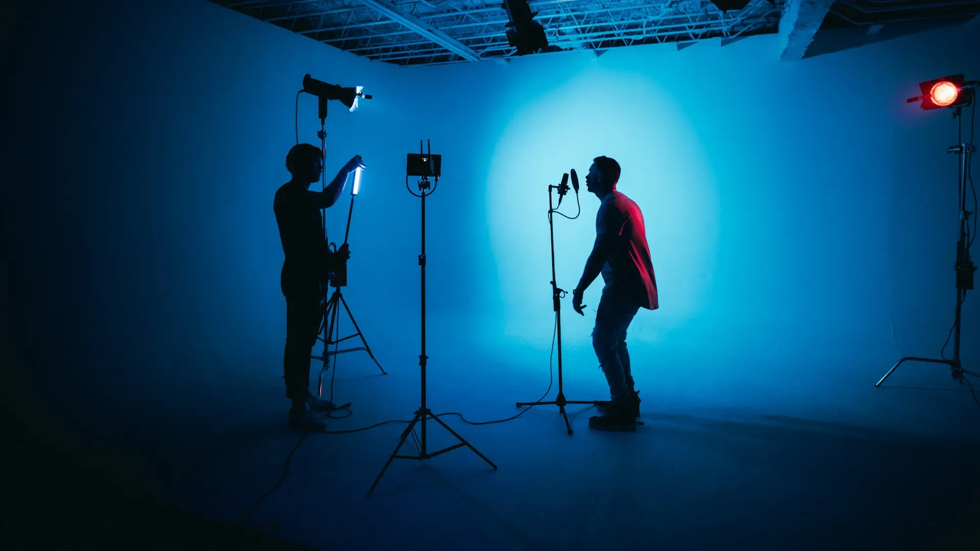un hombre de pie en el escenario usando una camisa roja y pantalones negros 
